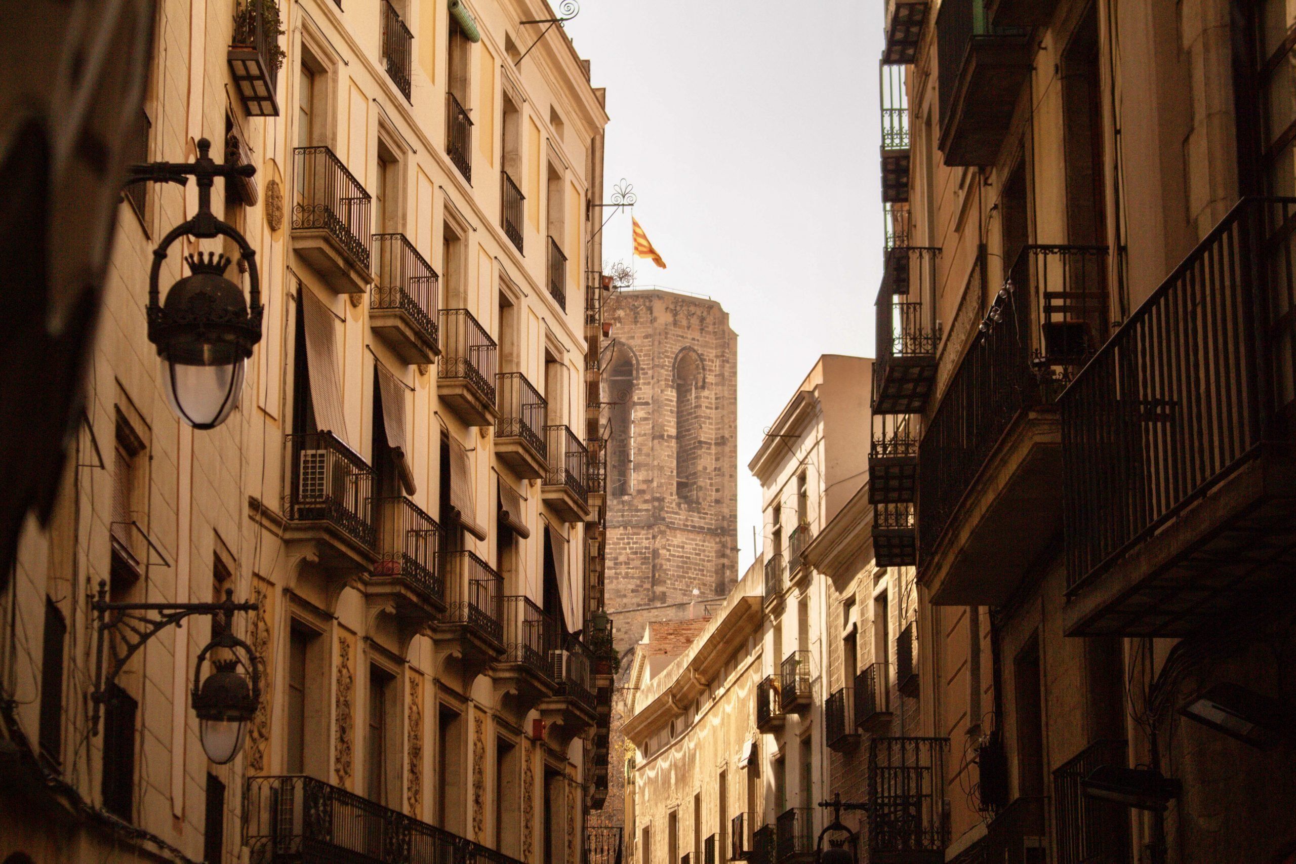 An image showing a street in the the Gothic Quarter of Barcelona leading up to an old church. 